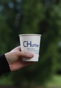 Hand holding a paper cup with the text "CHoffee"